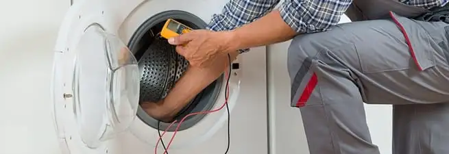 Dryer repair technician inspecting and repairing a clothes dryer in Kansas City, MO