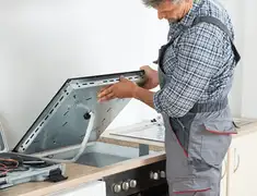 Appliance repair technician installing a built-in cooktop in Kansas City, MO