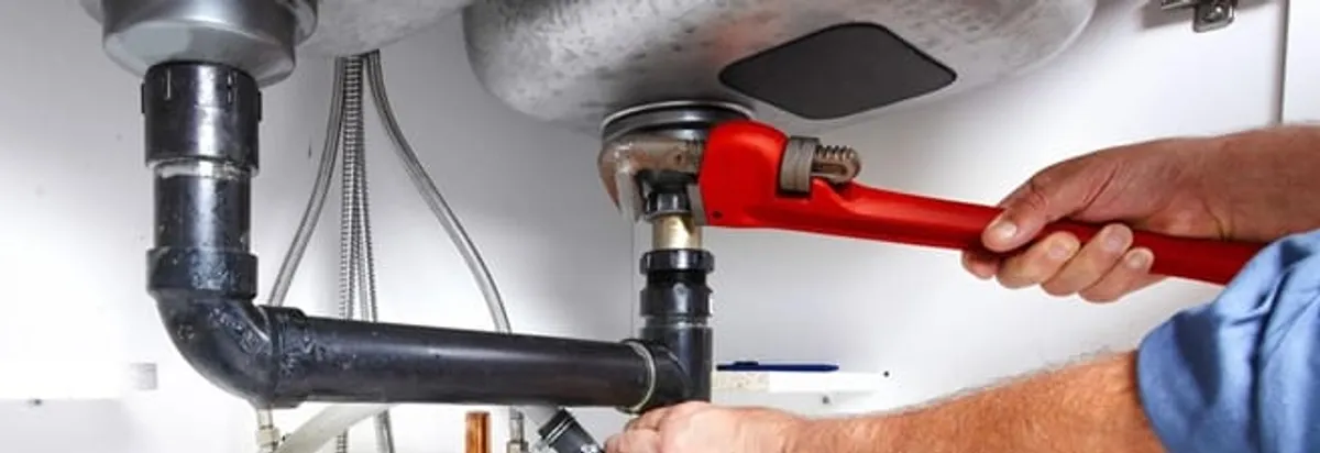 Garbage disposal repair technician tightening the sink drain and disposal connection in Kansas City, MO