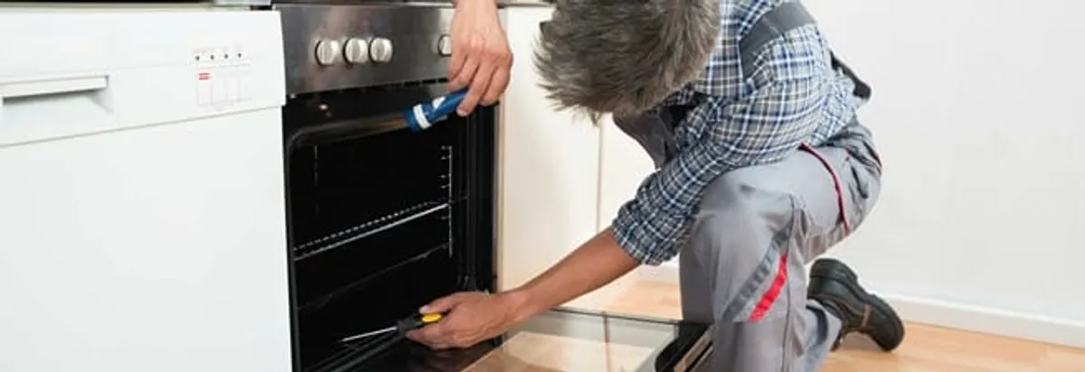 Oven repair technician inspecting and servicing an electric oven in Kansas City, MO