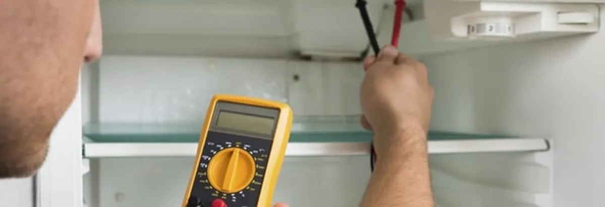 Refrigerator repair technician testing electrical components with a multimeter in Kansas City, MO