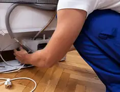 Appliance repair technician fixing refrigerator water line and connections in Kansas City, MO