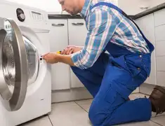 Washing machine repair technician servicing a front-load washer in Kansas City, MO