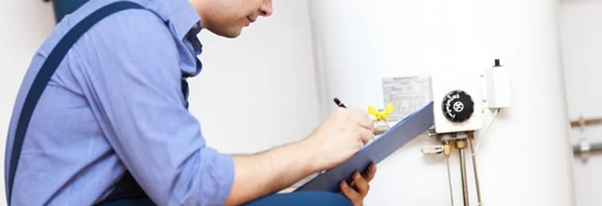 Water heater repair technician inspecting the unit and recording service notes in Kansas City, MO